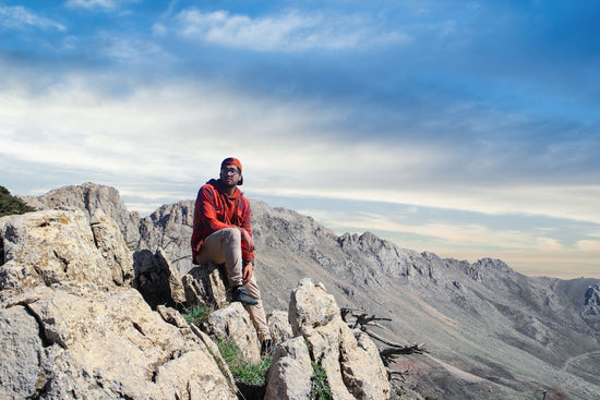 man in red jacket sitting on rock formation during daytime
