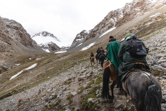 a group of people riding horses on a rocky trail
