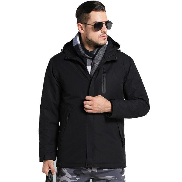 A person wearing sunglasses, a scarf, and a black winter jacket with a hood is shown against a white background. The jacket appears to have a zipper pocket on the chest.