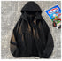 A black 3-in-1 mountain assault suit with a hood and a partially visible inner layer, laid out against a background of newspaper print.