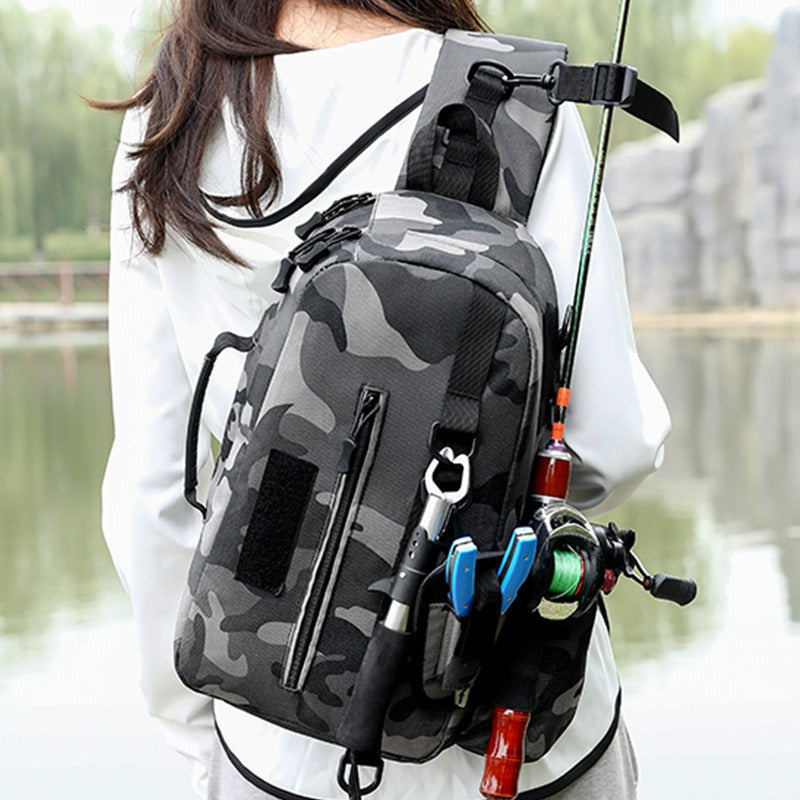A person wearing a gray camouflage Luya fishing pole chest bag diagonally across their back. A fishing rod is secured to the side of the bag, along with fishing pliers and other tools.
