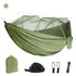 An olive green outdoor camping hammock with a fine white mosquito net suspended above it. Below are a matching olive green storage bag, two black tree straps, two black carabiners, and a bundle of green rope. A small olive green circle is in the upper left corner.