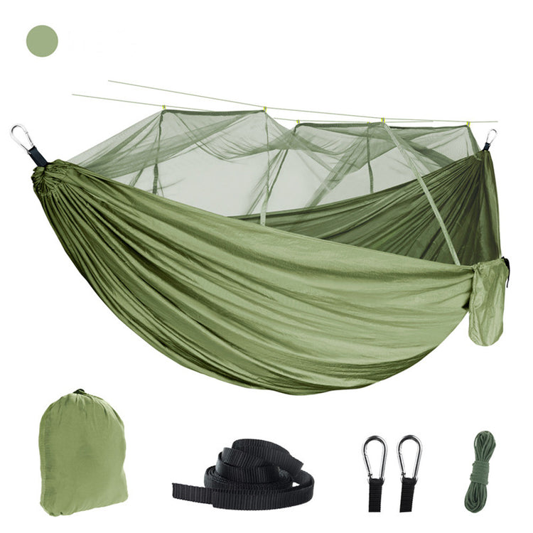 An olive green outdoor camping hammock with a fine white mosquito net suspended above it. Below are a matching olive green storage bag, two black tree straps, two black carabiners, and a bundle of green rope. A small olive green circle is in the upper left corner.