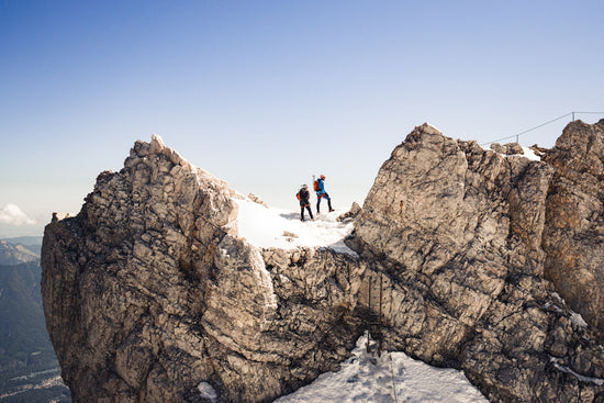 2 person sitting on snow covered mountain during daytime