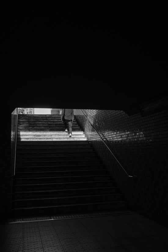 grayscale photo of man walking on stairs