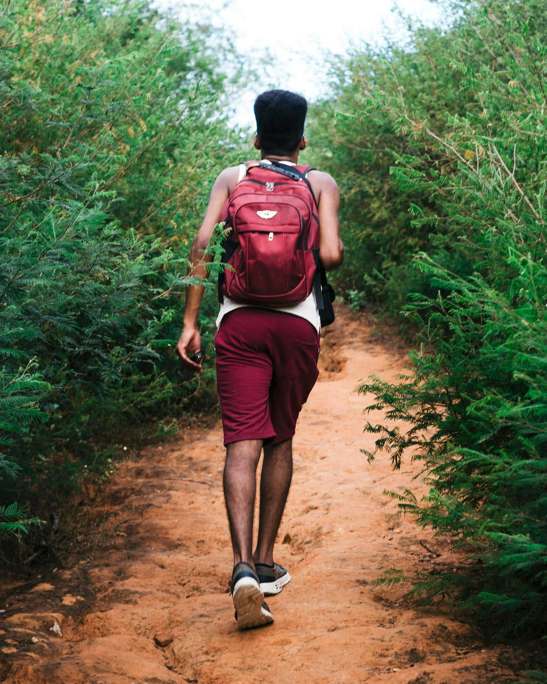 a man with a backpack walking down a dirt path