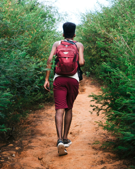 a man with a backpack walking down a dirt path