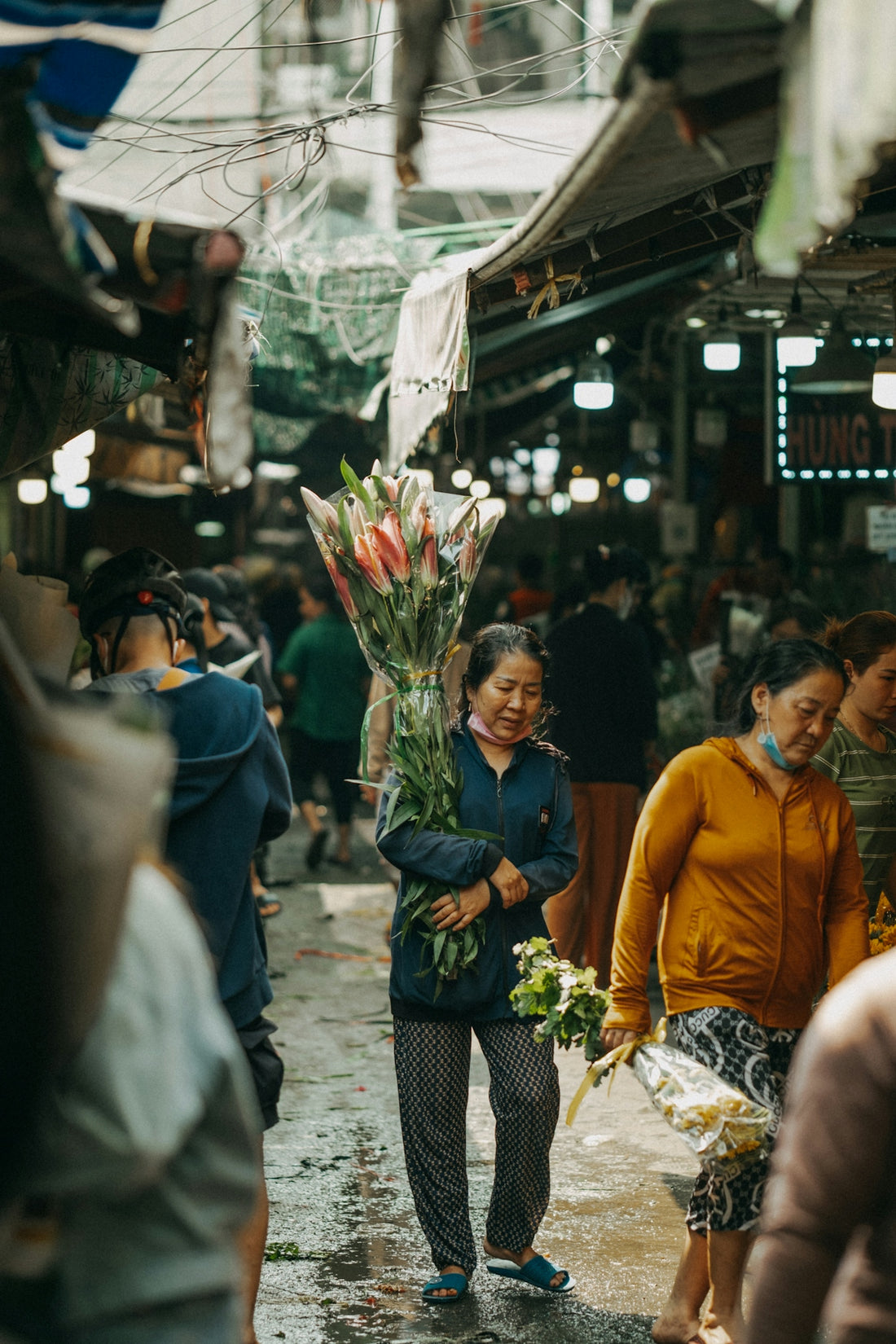 a woman walking down a street holding a bunch of flowers