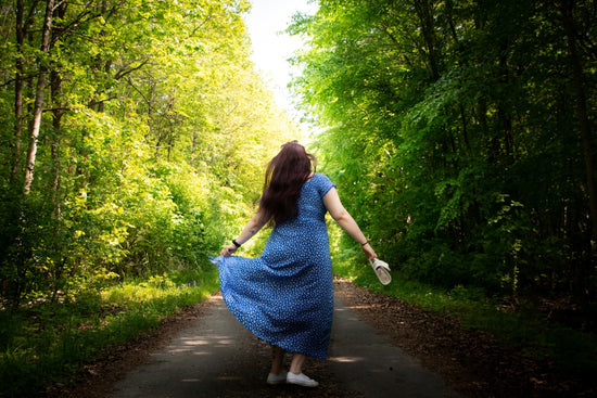 A woman in a blue dress is walking down a path