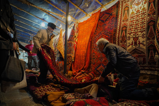 A group of people standing around a pile of rugs