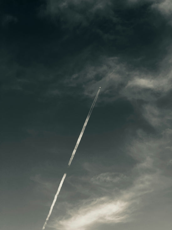 A jet flying through a cloudy blue sky