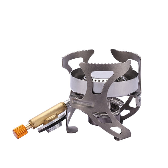 A small, silver and grey camping stove with three foldable pot supports extended is shown against a white background. A gold-colored gas valve with an orange adjustment knob protrudes from the side of the stove.