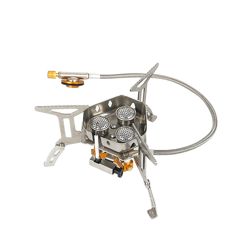 A compact, foldable camping stove with three burners and silver stainless steel construction is shown against a white background. A flexible gas line is attached to the side.