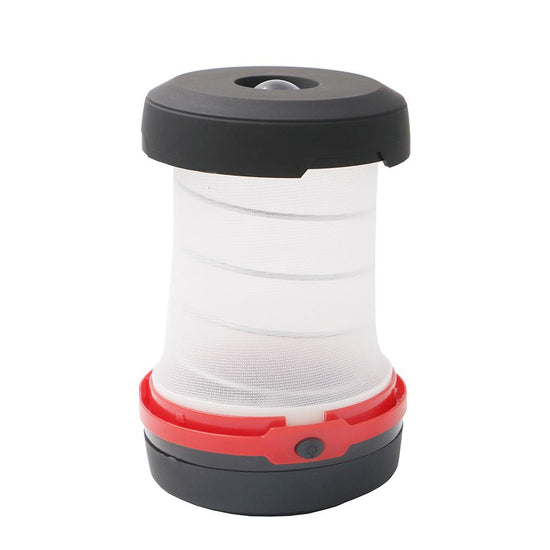 A compact camping lantern with a black top and base, a translucent white collapsible middle section, and a red band with a button is shown against a white background. The lantern is in its collapsed state.