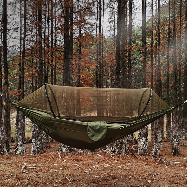 An olive green camping hammock with a black mosquito net extended above it is shown. Below the hammock are two silver carabiner clips attached to black straps, a coiled black tree strap, and an olive green stuff sack.