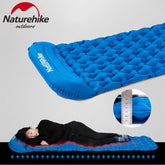 A blue inflatable camping mat with a diamond-shaped air cell pattern and an integrated pillow is shown fully inflated next to its blue stuff sack and the blue inflatable pump bag. Text indicates "Naturehike outdoors," "Inflatable Bag + Mattress (With Pillow)," dimensions, weight, and the color "Blue.