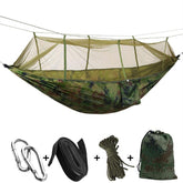 An ultralight camouflage two-person camping hammock suspended between two points, featuring a built-in fine mesh mosquito net enclosing the sleeping area.