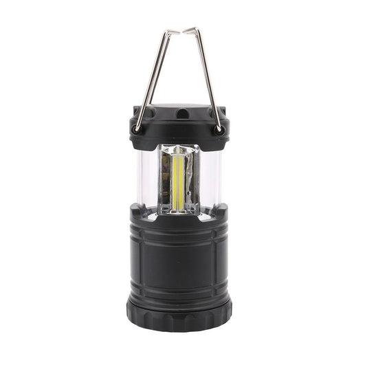 A compact black collapsible camping lantern with a clear plastic body showing three bright COB LED light strips. It has a silver metal carrying handle extended upwards.