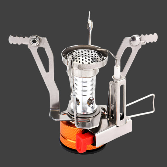 A very small, silver and orange camping stove with foldable pot supports extended is shown next to its bright orange plastic carrying case against a stark white background. The stove has a small red lever for controlling the gas flow and a visible piezo igniter.