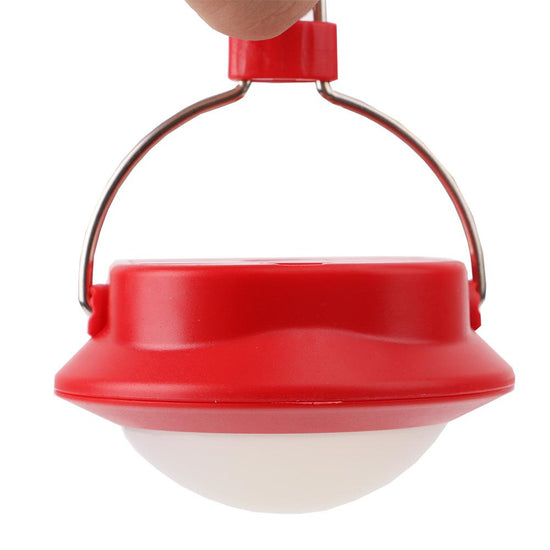 A red and white portable LED camping lantern with a silver hanging hook is shown held by a finger against a white background.