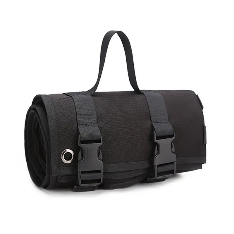 A rolled-up black shooting mat secured with two buckled straps and a carrying handle is shown against a white background. A metal grommet is visible on the side.
