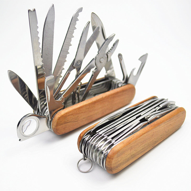A multi-functional stainless steel folding tool with a wooden handle is shown open against a white background, revealing numerous blades, saws, pliers, and other tools extended.