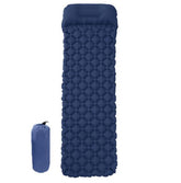An inflated blue camping sleeping pad with a pillow section is shown next to its deflated and packed-down form in an orange stuff sack, both against a white background. The pad has a diamond-shaped air cell pattern.