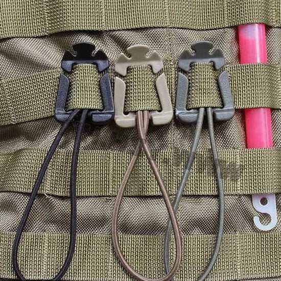 Three MOLLE Grimloc D-ring locking carabiner clips in black, khaki, and army green are shown attached to olive green MOLLE webbing. Each clip has a spring-loaded gate and a cord loop extending from the bottom.