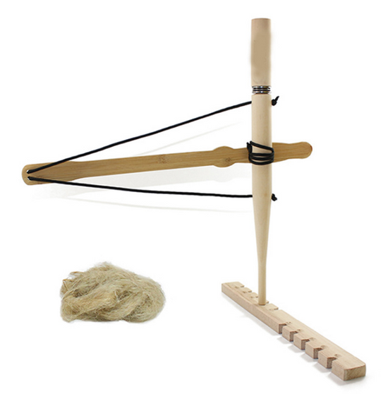 A bow drill fire starter kit is shown against a white background. The kit includes a wooden bow with a black cord, a long wooden spindle, a wooden fireboard with pre-cut notches, and a small pile of fibrous tinder.